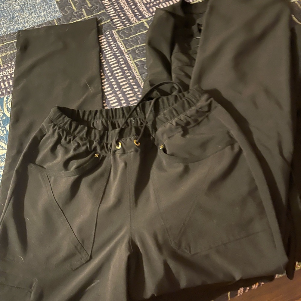 2 pair of black Infinity scrubs with an Infinity Scrub jacket